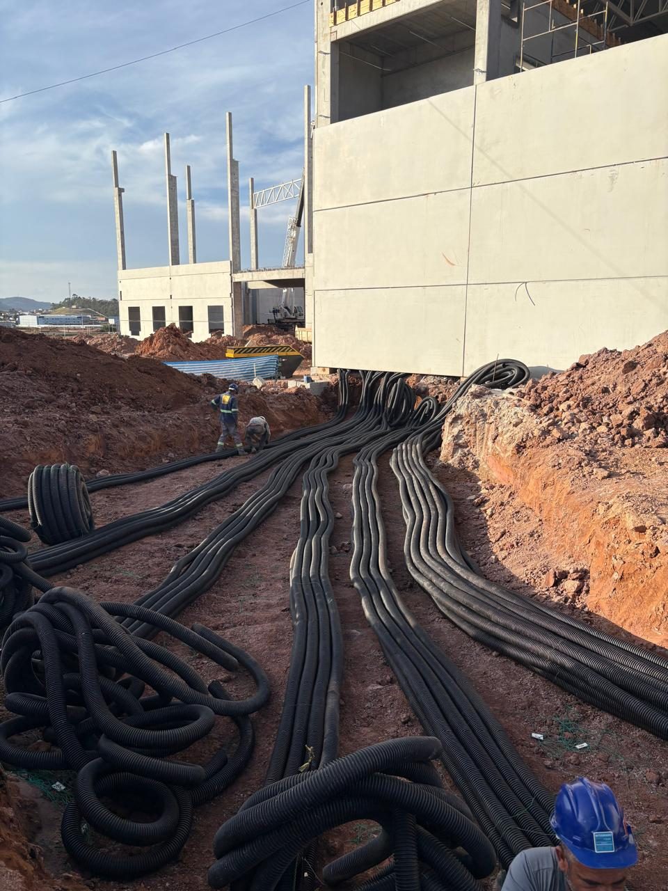 Feixes de eletrodutos lançados na vala ao lado do prédio, antes do reaterro