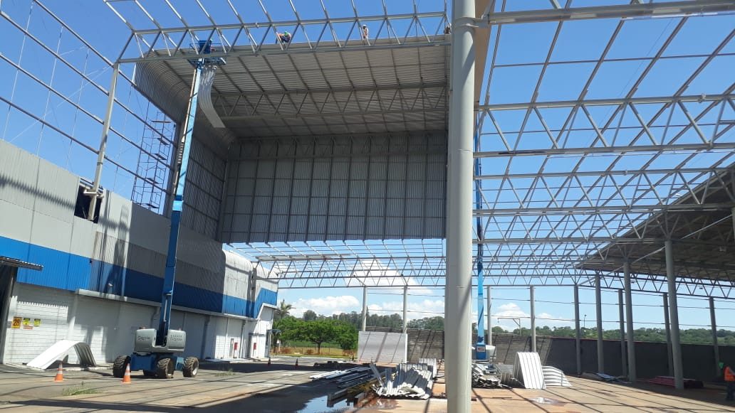 Fachada de galpão com plataforma elevatória durante a montagem