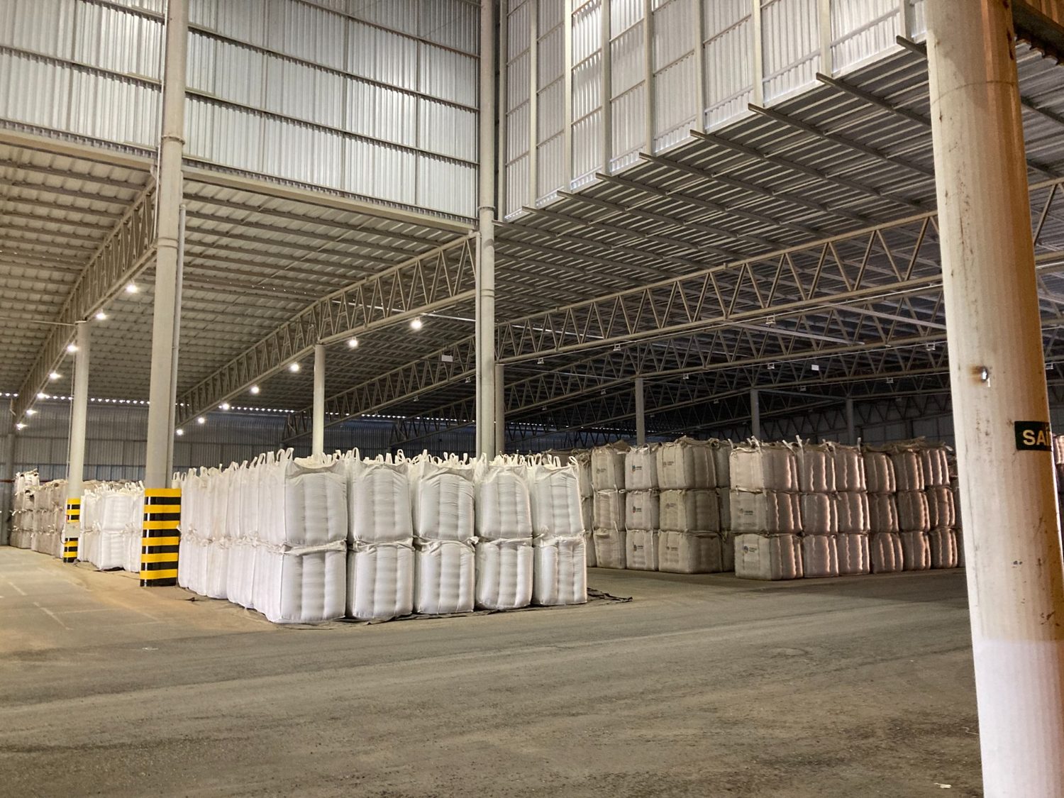 Interior do galpão da CofcoAgri com big bags empilhados sob a estrutura metálica
