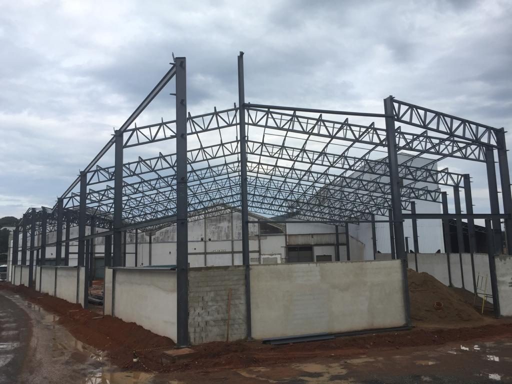 Estrutura metálica da obra da Comexim durante a montagem, com pórticos contra o céu