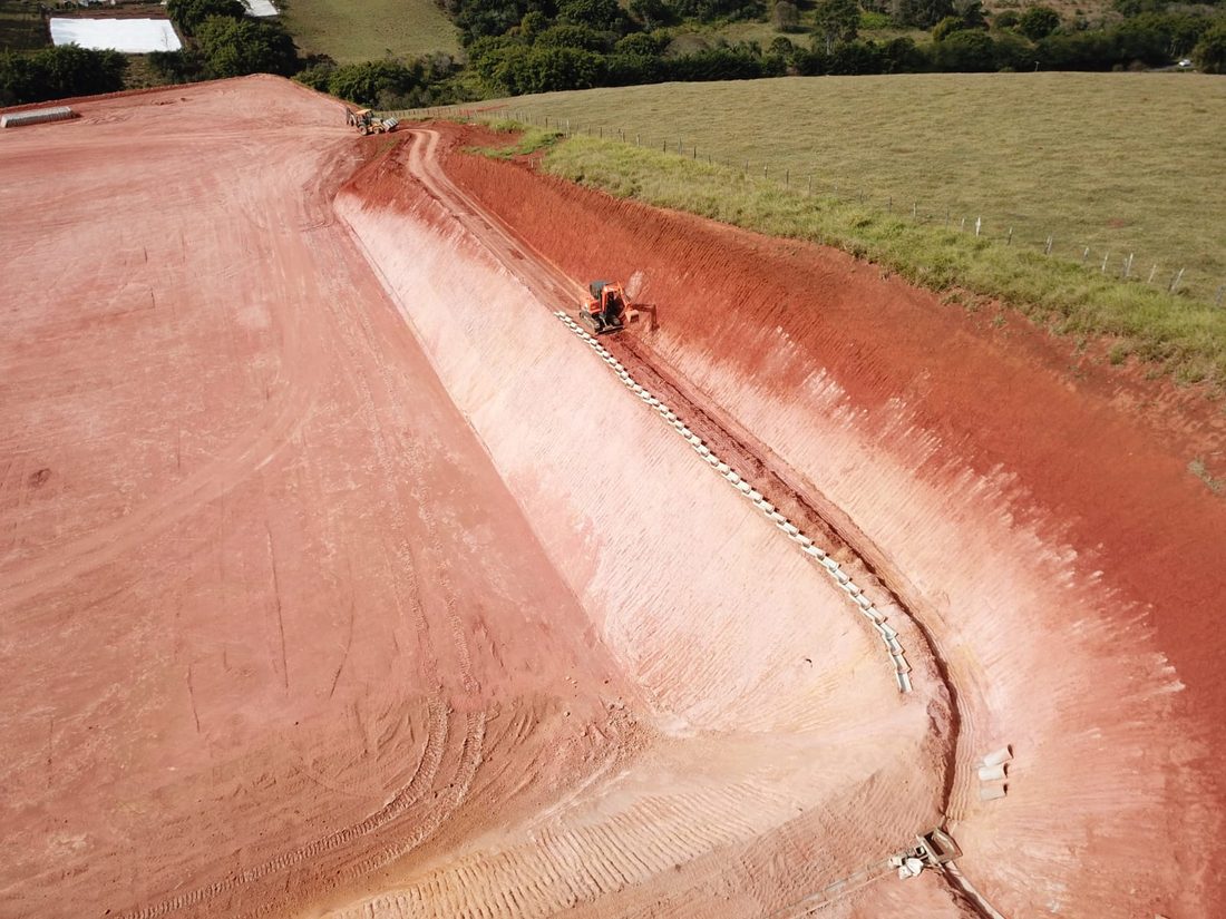 Talude alto de terraplanagem com máquina trabalhando no pé