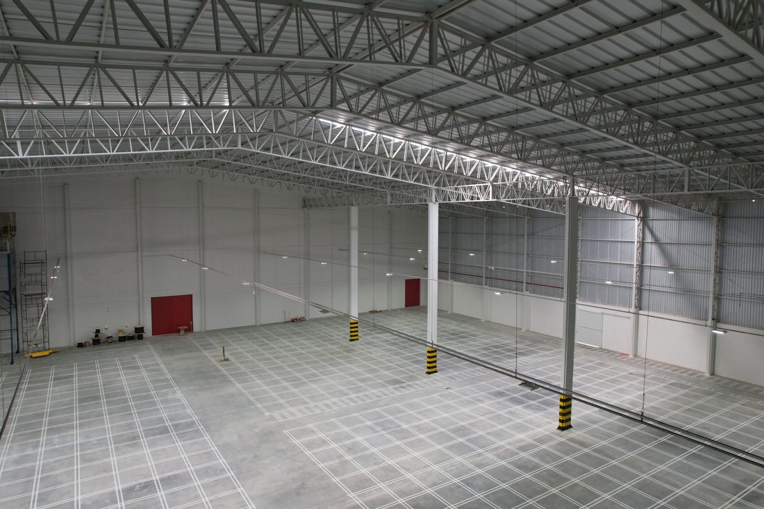 Interior do armazém acabado, com piso concretado e demarcação