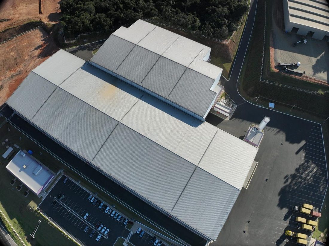 Vista aérea próxima da cobertura, com o estacionamento e o pátio de carretas